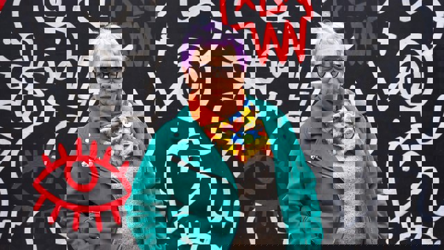 Kvinna i färgstarka kläder och lila hår. 