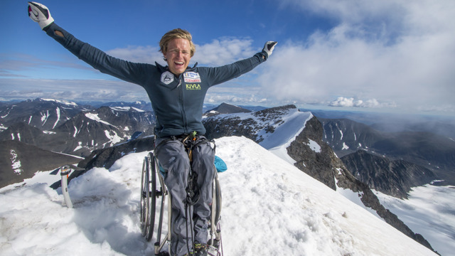 Fotografi av Aron Anderson, sittandes i rullstol på en bergstopp.