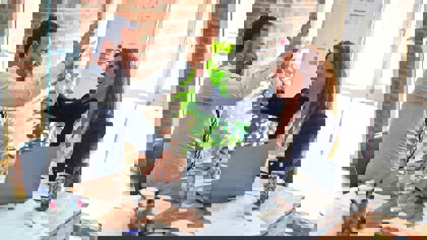 En man och en kvinna gör en high five i kontorsmiljö.